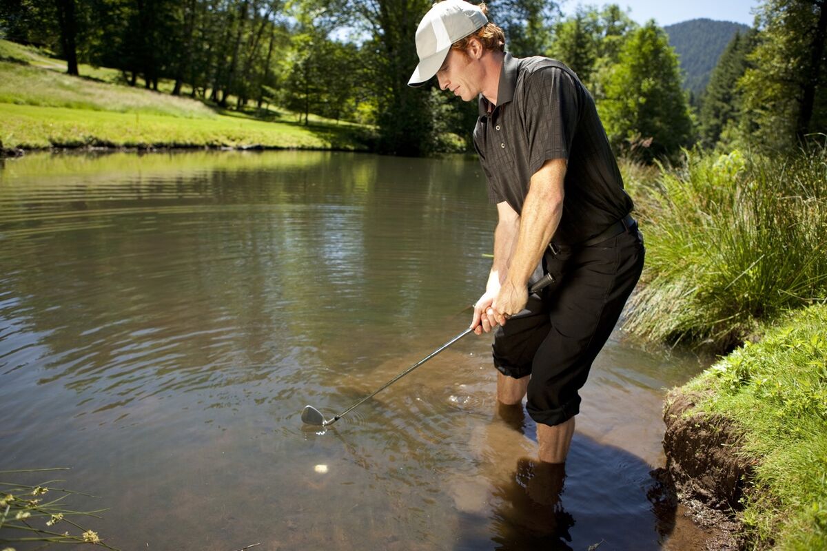 Golfer plays from in the water