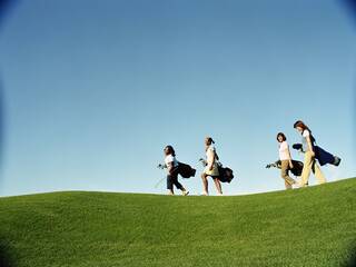 Four golfers walk up a fairway