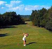 Woman teeing off down a long green