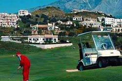 Red-clad golfer and a collection of mountain homes, with his cart beside him