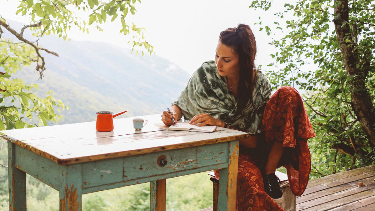 woman writing outdoors at table