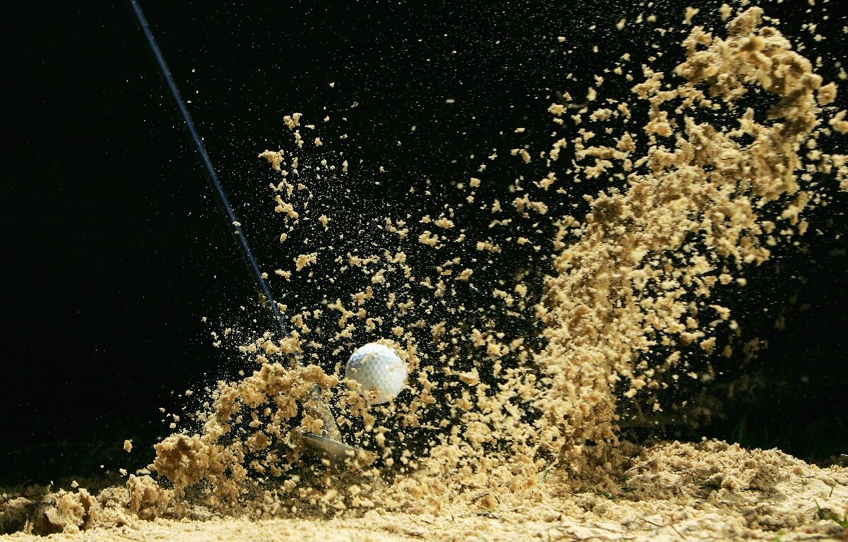 golf club hitting a bunker shot