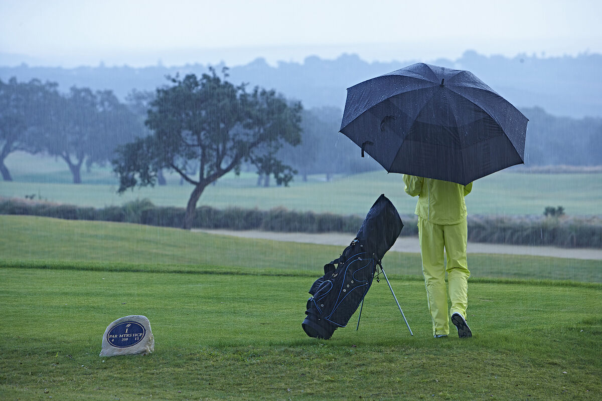Golfer using umbrella on rainy day