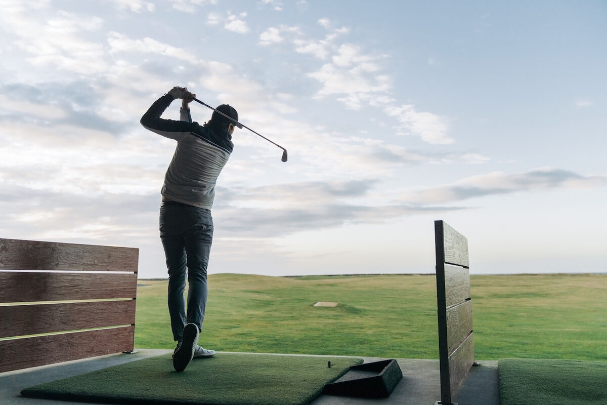 Man swinging club at driving range