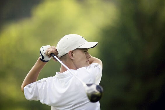 Golfer wearing white hat during swing