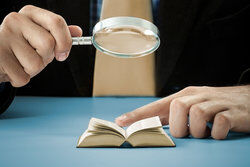 reading small book with magnifying glass