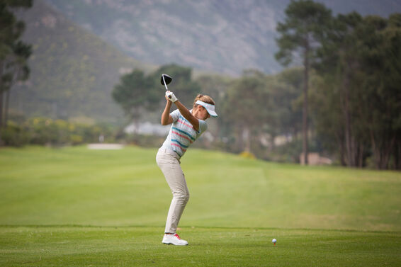 woman swinging golf club on course