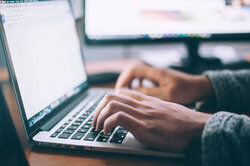 person typing letter on laptop