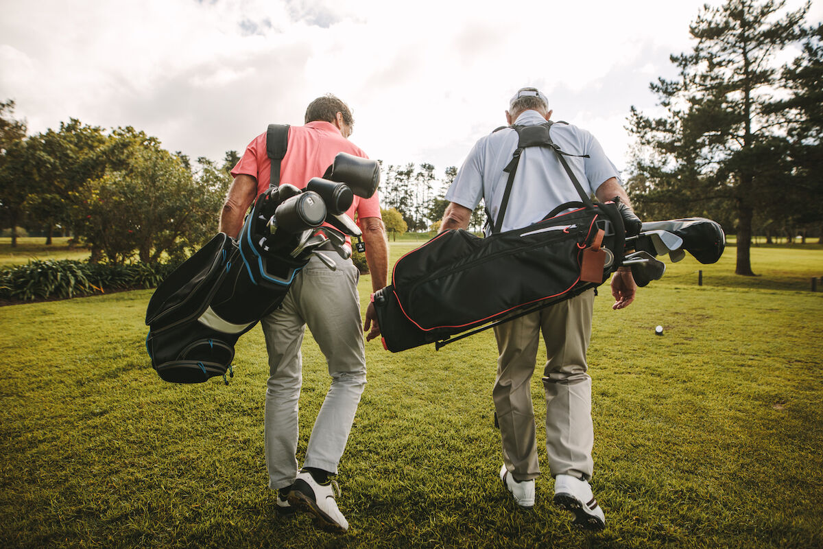Two golfers carrying golf bags