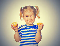 young girl holding orange halves