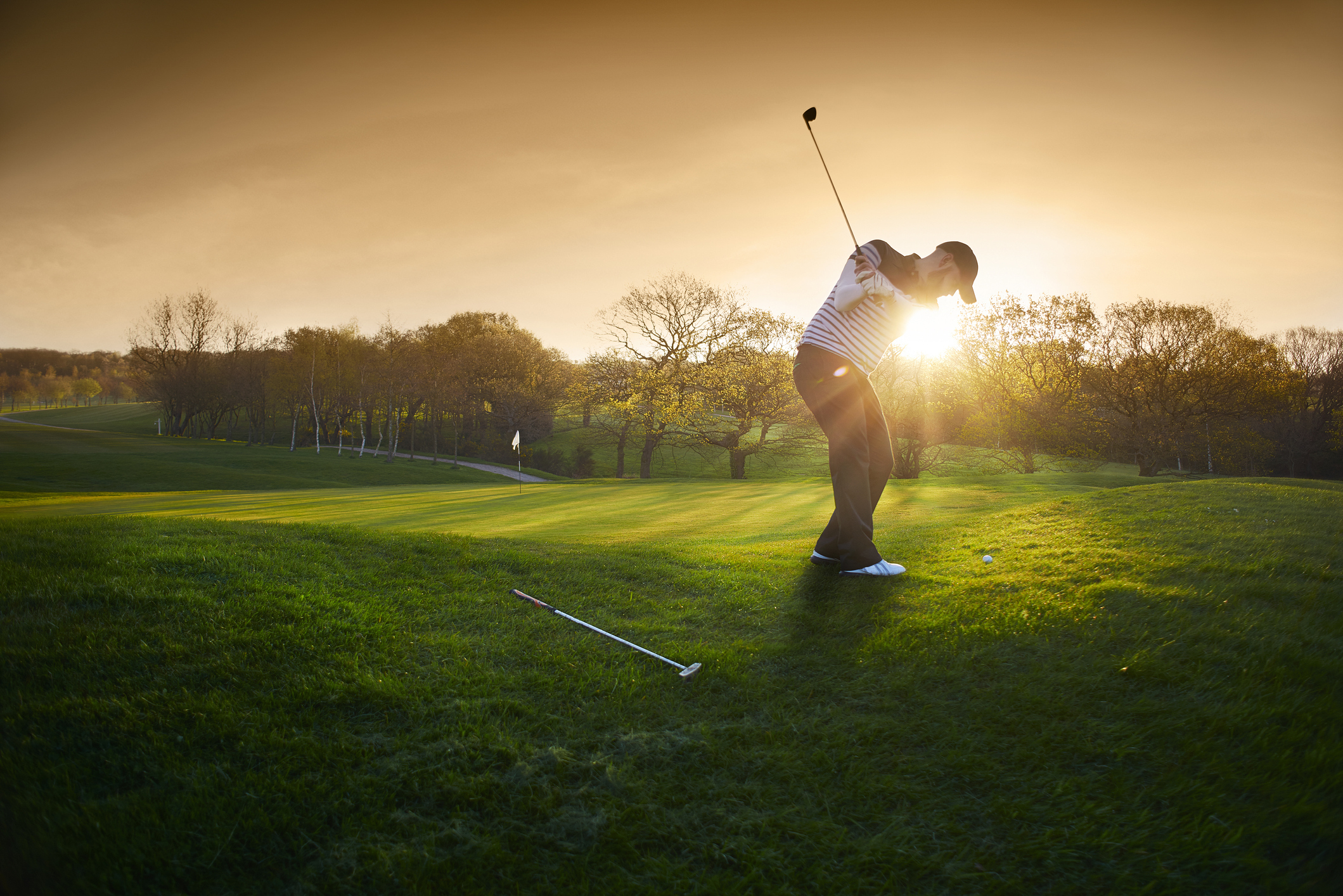 Golfer hits a shot at sunset Golfer hits a shot at sunset