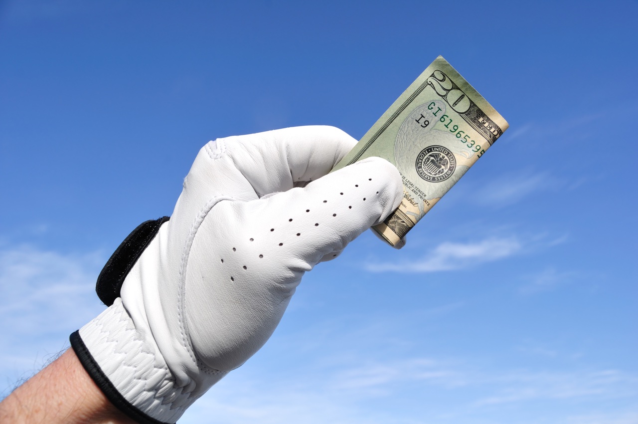 Golfer holds a $20 bill towards the sky