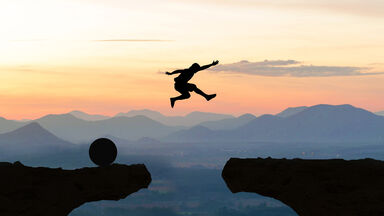 man jumping from one rock ledge to another at sunset - Two Spaces After a Period
