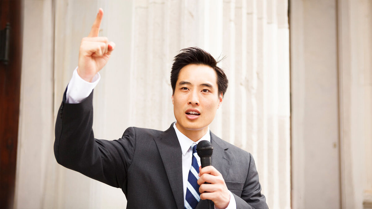 Man waving finger and holding microphone as declamation example
