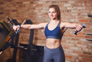 Woman doing lateral raise with dumbbells