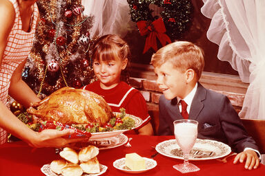 Mother showing roast turkey to children at Christmas meal