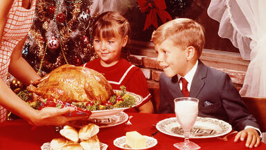 Mother showing roast turkey to children at Christmas meal Mother showing roast turkey to children at Christmas meal