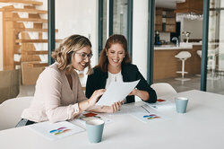 two businesswomen going through paperwork together in an office