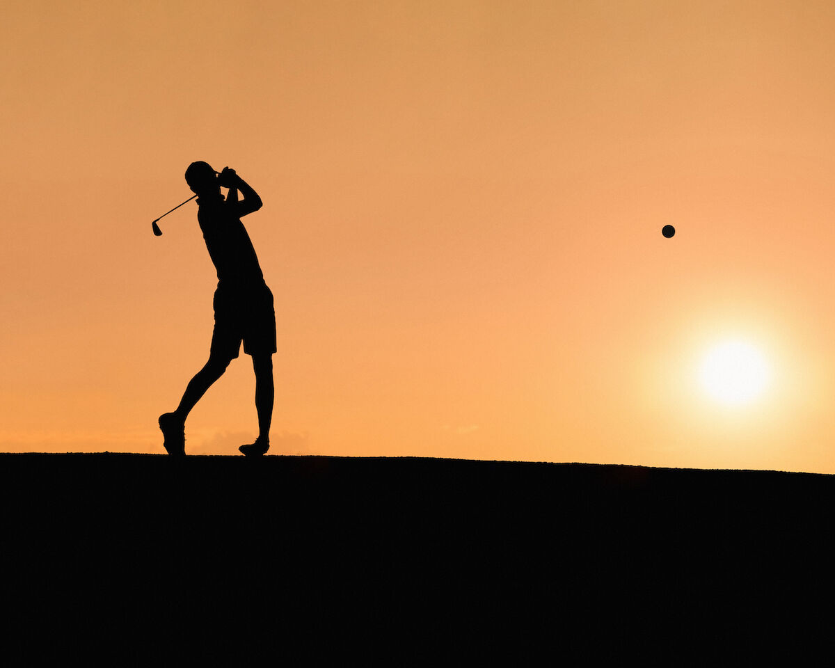 golfer hitting perfect shot in sunset