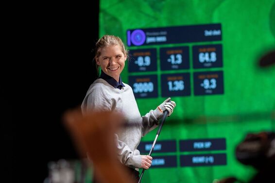 woman smiling with TrackMan Golf simulator