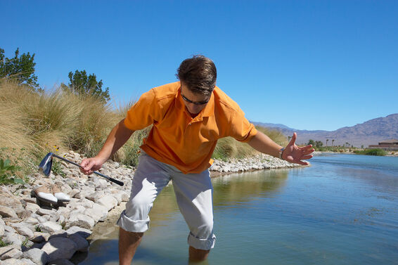 Golfer looking for ball in water