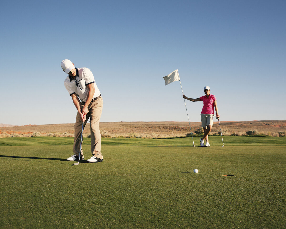 Golfer sinking putt with flag out