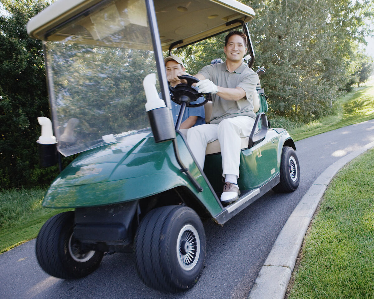 Man driving golf cart on path