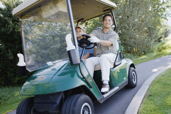 Man driving golf cart on path