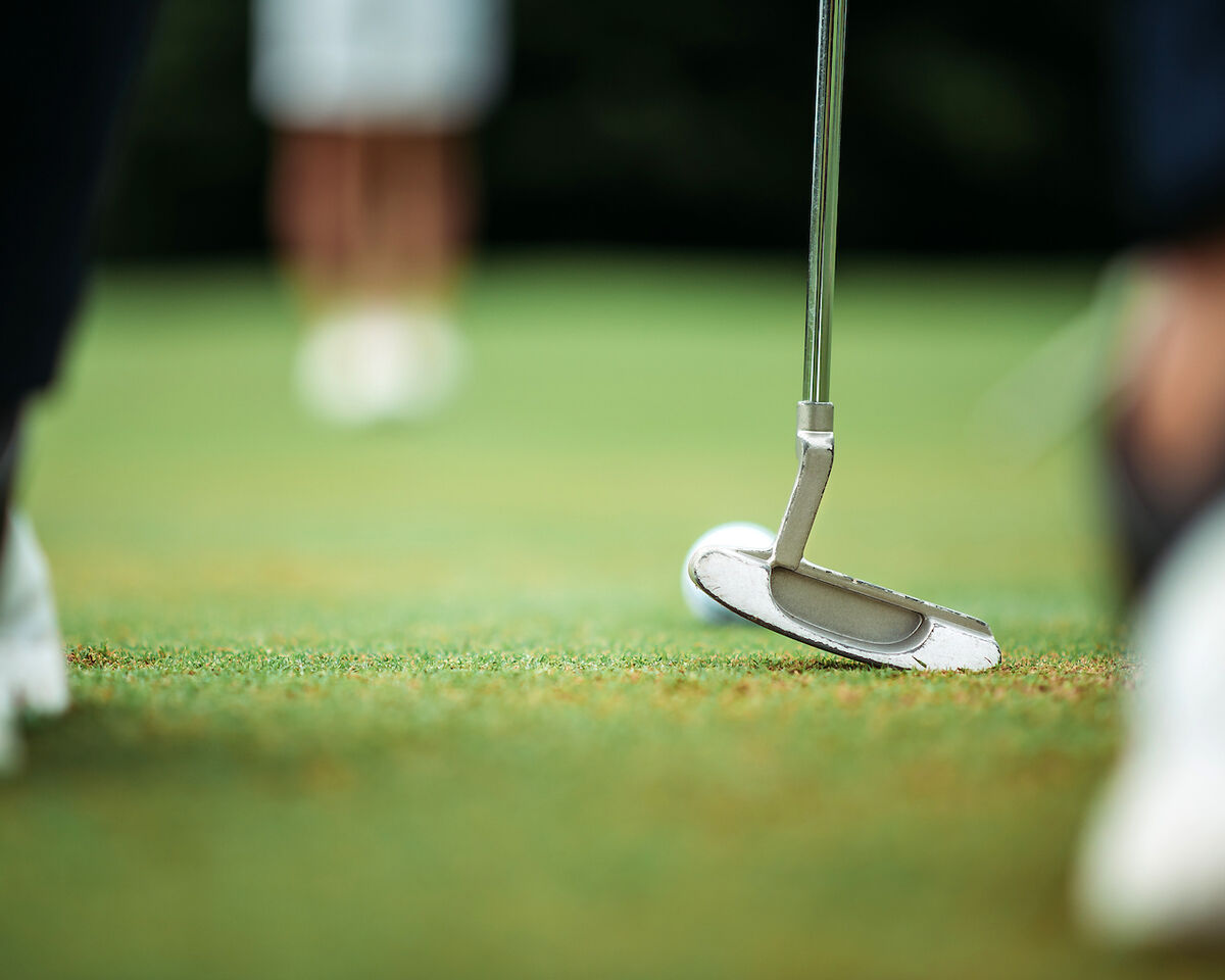 Putter and ball on putting green