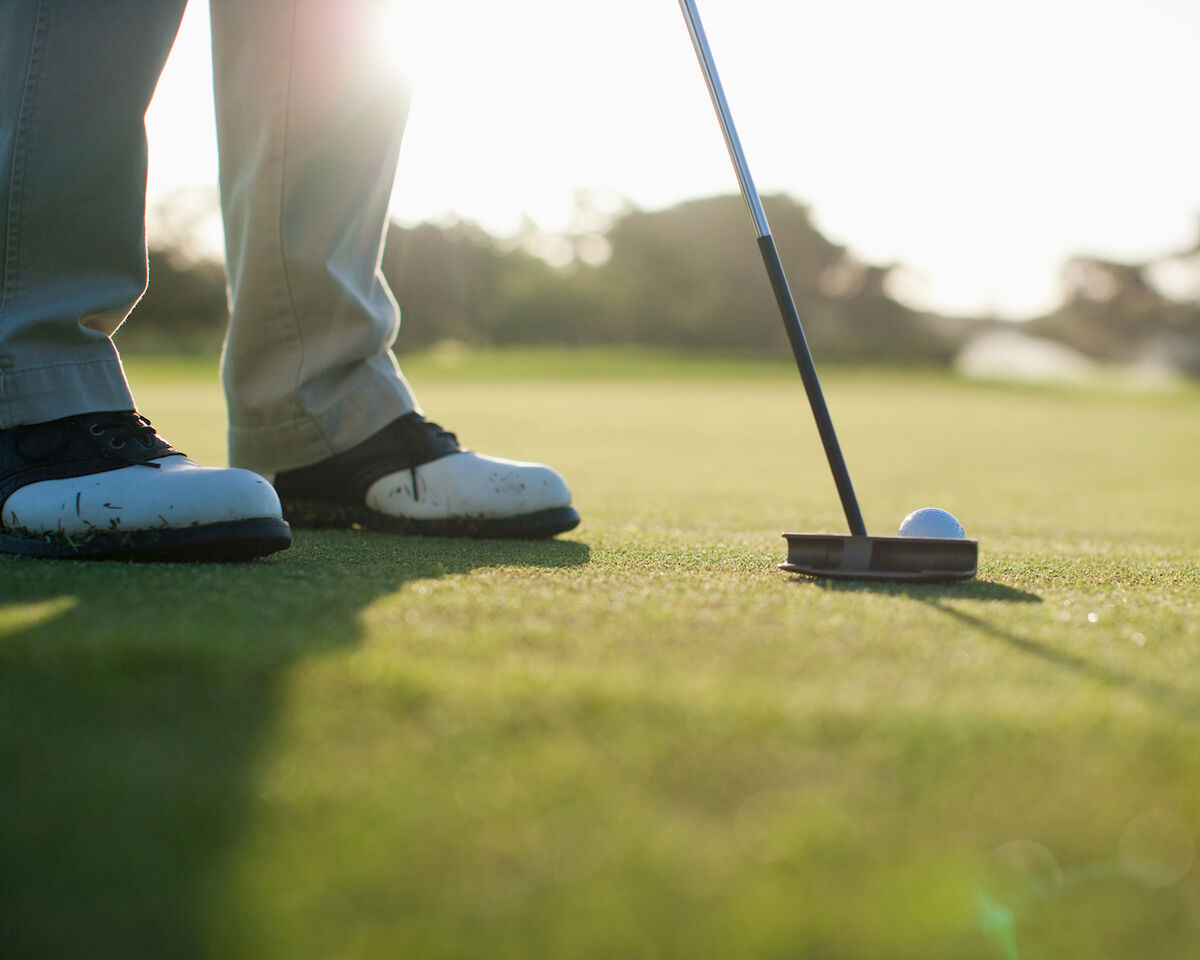 Golfers feet with putter and ball