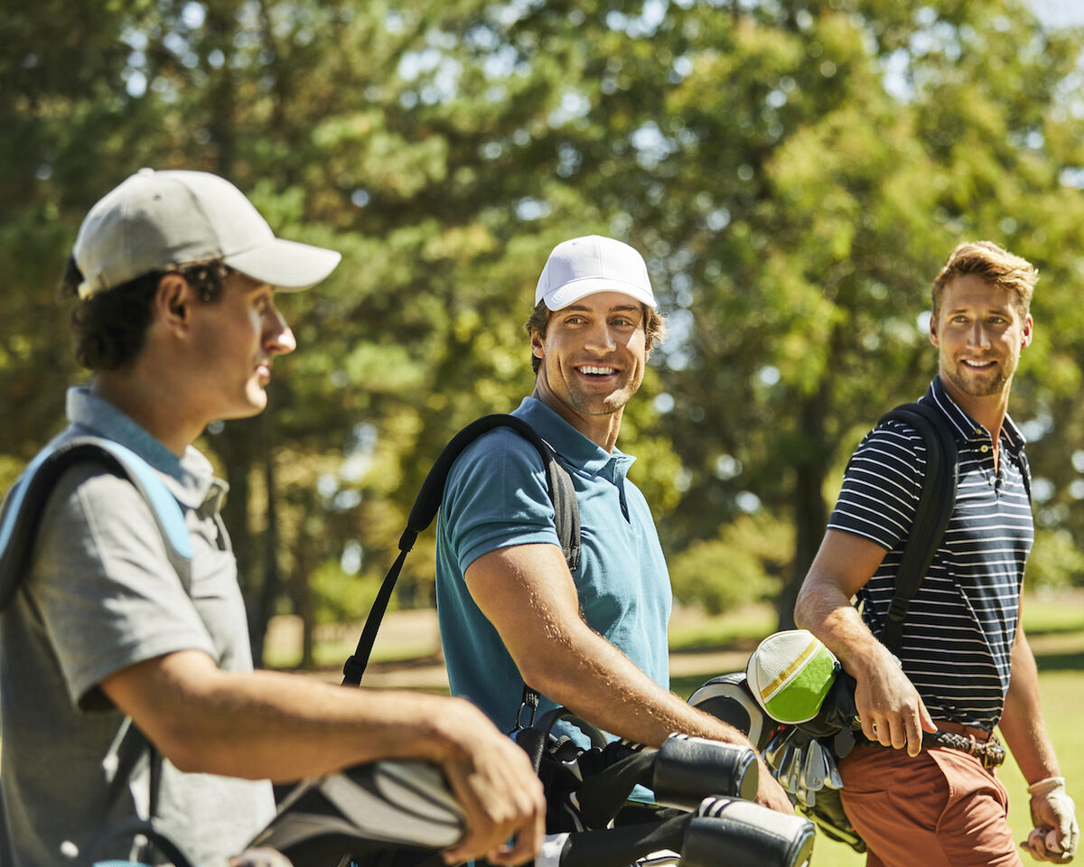 Three golfers smiling on course