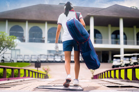 Golfer carrying clubs in travel bag