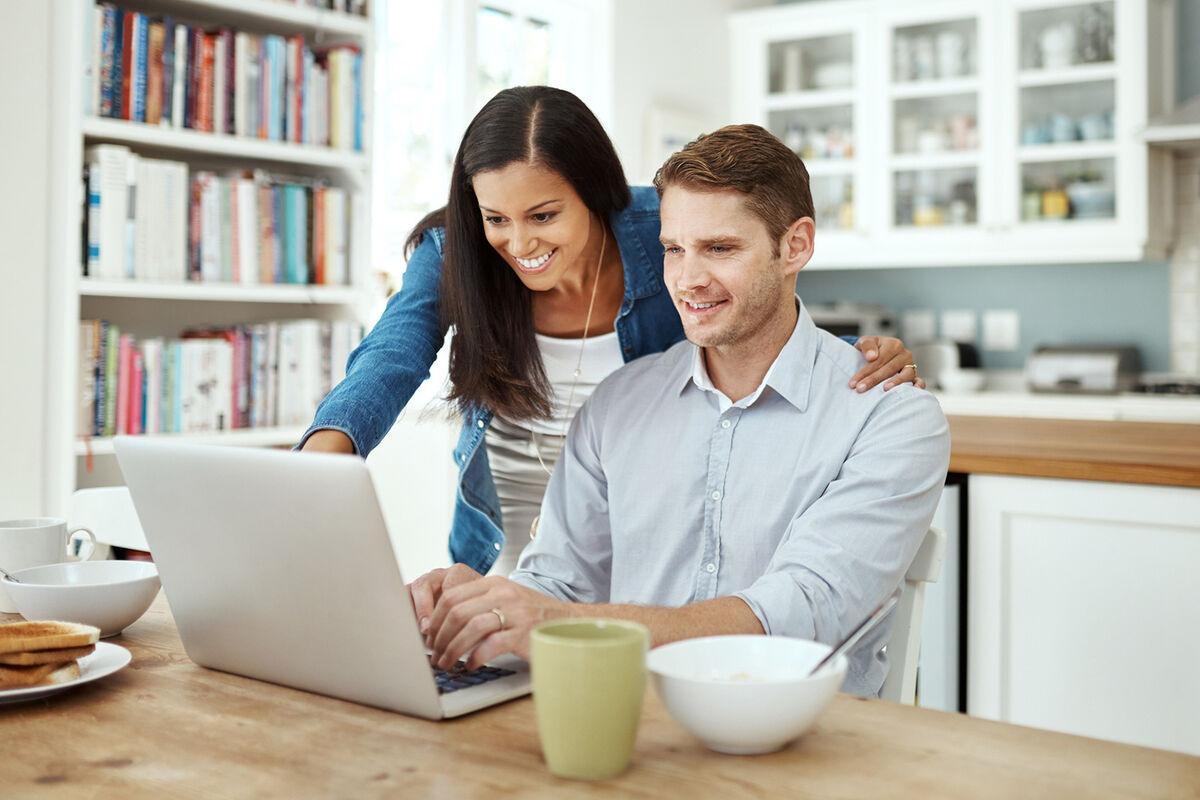 Couple using a laptop together at home