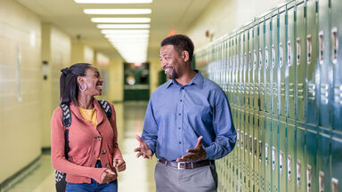 Teacher and high school student talking in hallway