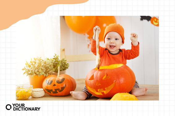 happy baby in pumpkin costume dipping wooden spoon into jack-o'-lantern
