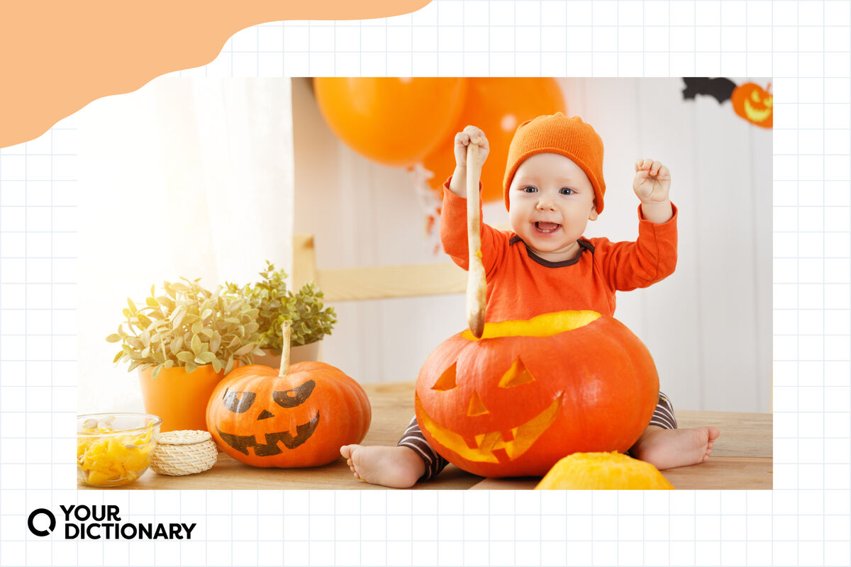 happy baby in pumpkin costume dipping wooden spoon into jack-o'-lantern