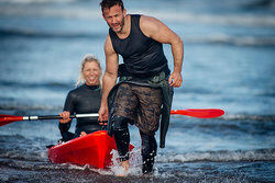 man bringing woman to shore in kayak