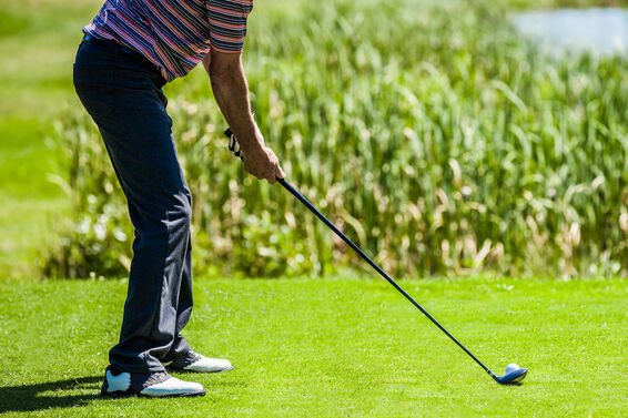 golfer addressing ball with hybrid club