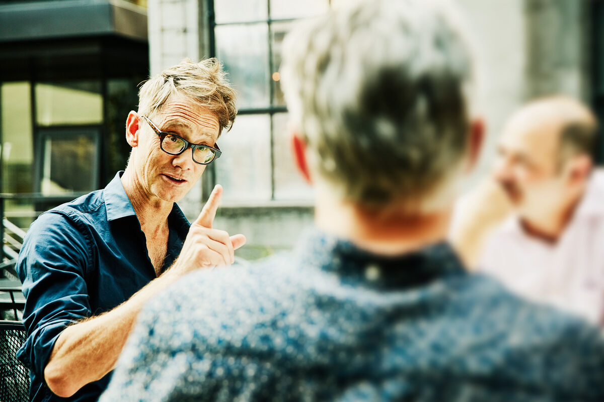 man pointing finger in discussion with friends