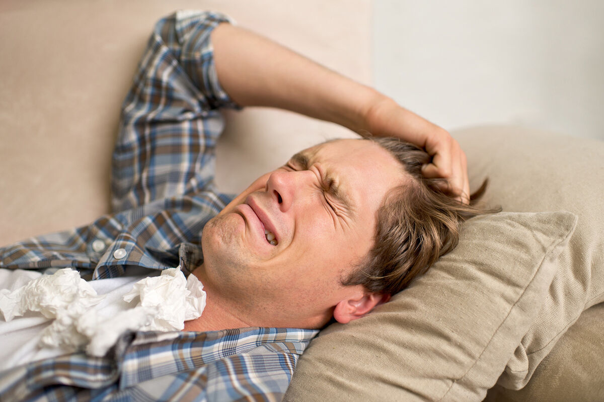 Man crying while lying on the sofa with tissues