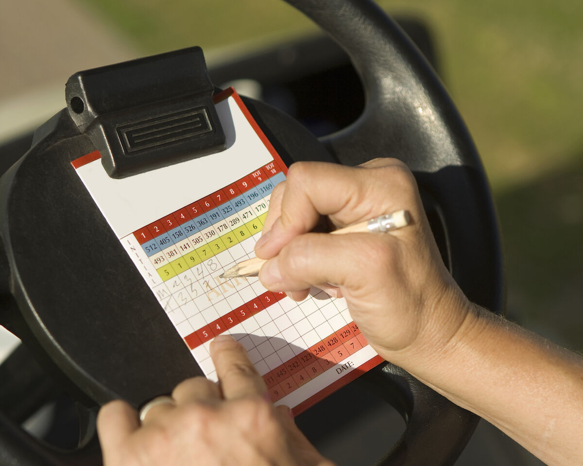 golfer writing on scorecard on cart