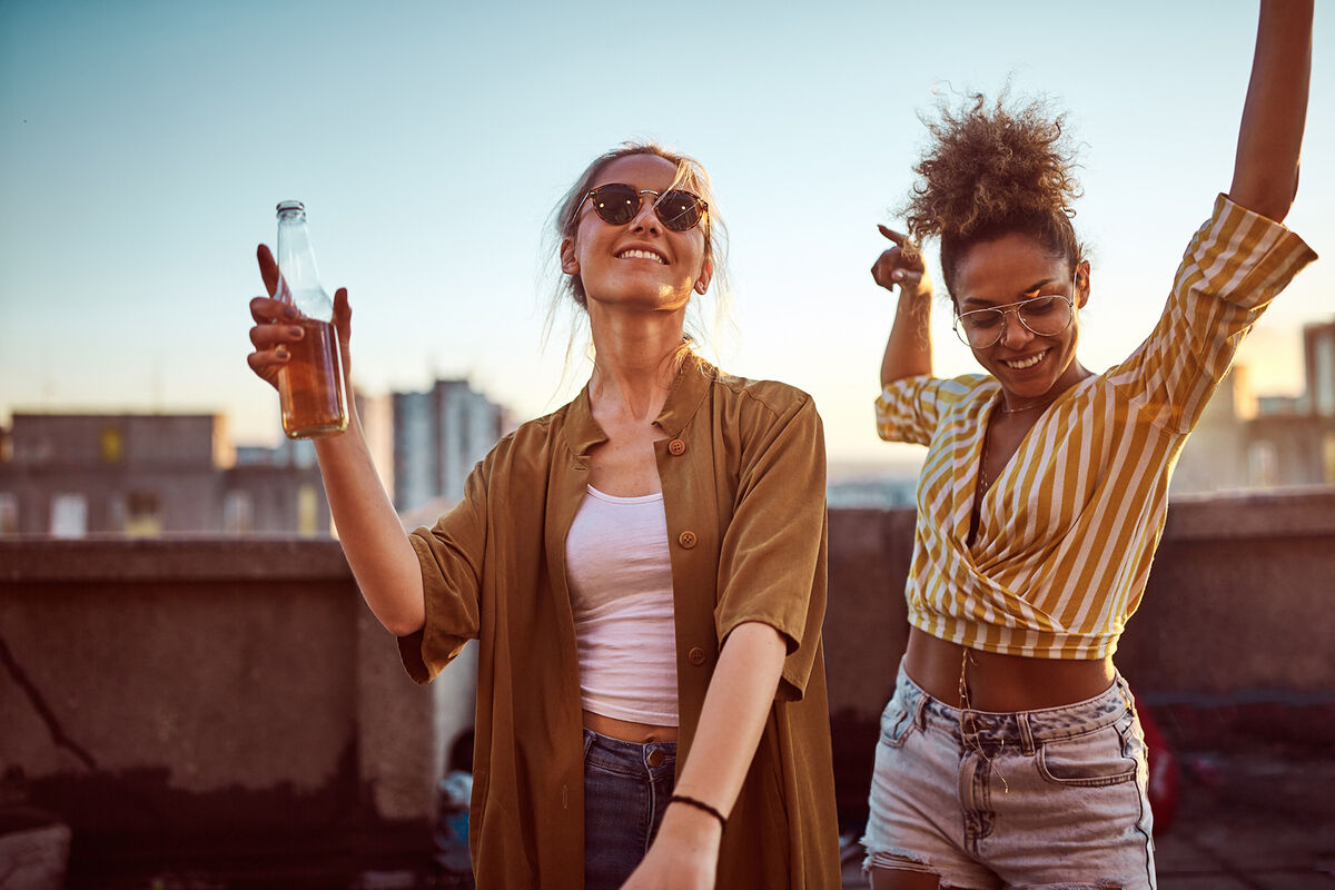 Two women dancing and drinking alcohol at the party