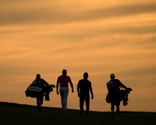 Golfers and caddies walking at twilight