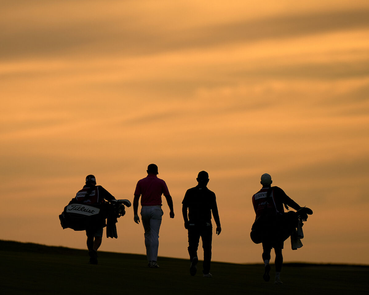 Golfers and caddies walking at twilight