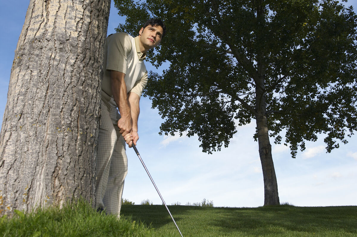 Golfer stuck behind a tree