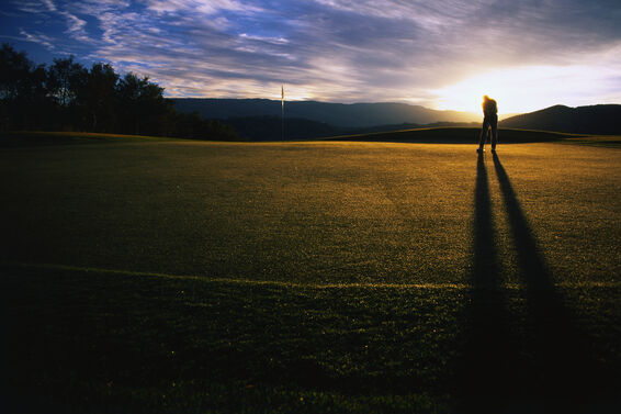 Golfer putting a dusk