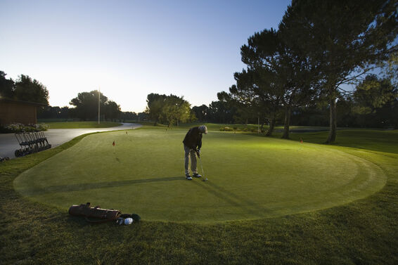 Golfer practicing putting distance control at dawn