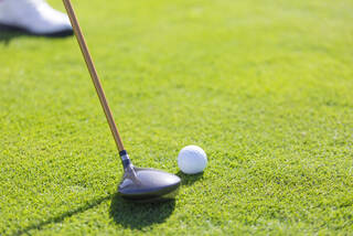 Golfer using a 7 wood to address the ball