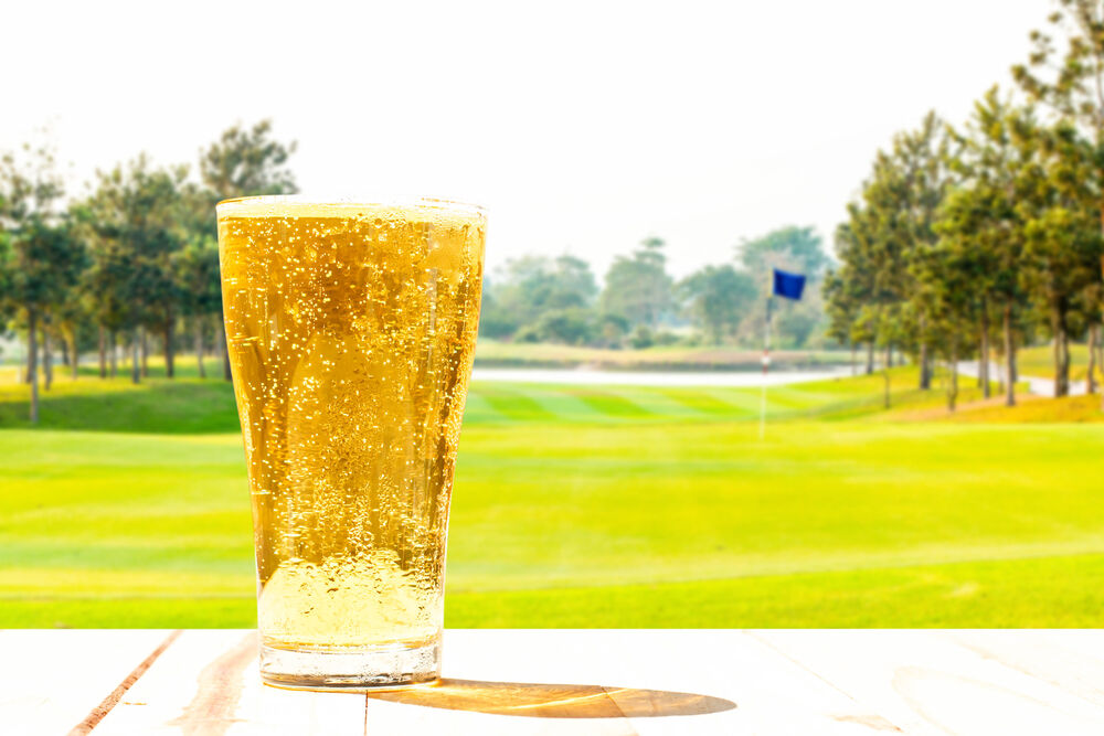 A glass of beer sits at the 19th hole overlooking the last green