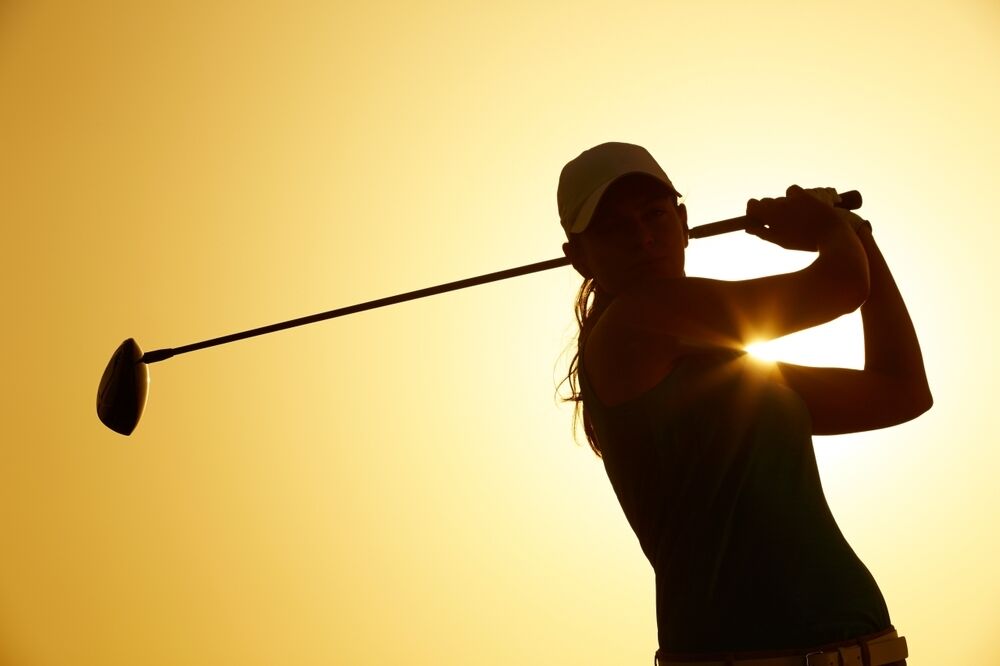 Silhouette of a woman hitting a golf shot